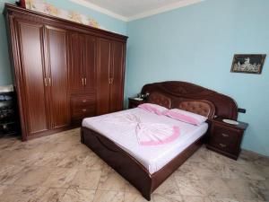Schlafzimmer mit einem Bett mit einem Kopfteil aus Holz und Holzschränken in der Unterkunft Casa Shtoj I Vjeter, Shkoder 
