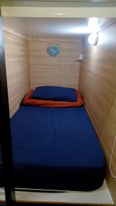 a small bedroom with a blue bed in a boat at BRICKS Backpackers Sleepbox in Tanah Rata
