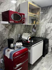 a kitchen with a red stove and a microwave at Meu Loft Barra Nova 3 in Saquarema