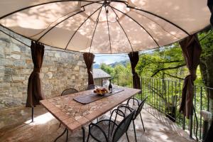 einen Tisch und Stühle auf einer Terrasse unter einem Sonnenschirm in der Unterkunft La Fonte di Mariella Monolocale 1 in Dosso del Liro