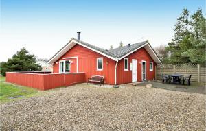 une maison rouge avec une table de pique-nique devant elle dans l'établissement Cozy Home In Blvand With Kitchen, à Blåvand