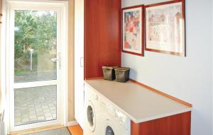 - une buanderie avec un lave-linge et un sèche-linge à côté d'une porte dans l'établissement Cozy Home In Blvand With Kitchen, à Blåvand