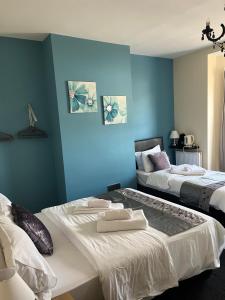 two beds in a room with blue walls at The Harp Freehouse and Guesthouse in Ipswich