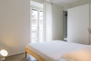 a white bedroom with a bed and a window at Palermo Flexyrent Apartment in Milan