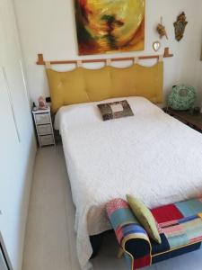 een slaapkamer met een wit bed met een geel hoofdeinde bij CASA degli OLIVI GARDA LAKE in Riva del Garda