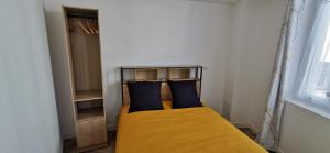 una camera da letto con letto giallo e cuscini blu di Appart Cosy Place Saint-Jean a Niort
