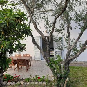 a patio with a table and chairs and trees at Apartman Pelargo in Poljana