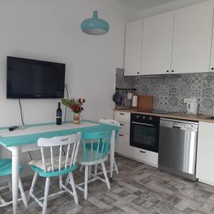 a kitchen with a table with chairs and a television at Apartman Pelargo in Poljana