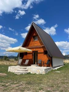eine Blockhütte mit Stühlen und einem Sonnenschirm in der Unterkunft Planinska iskra in Žabljak