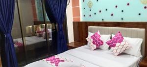 um quarto com uma cama com almofadas cor-de-rosa e brancas em HOTEL OM SAI em Vovale
