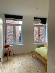a bedroom with a bed and a chair and windows at T3 lumineux en plein coeur de Moulins in Lille