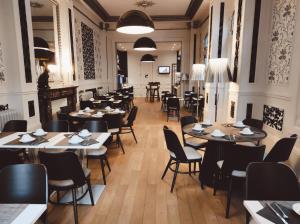 a restaurant with tables and chairs and a person in the background at Hôtel de Paris in Besançon