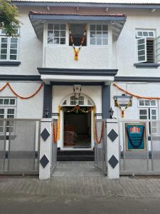 ein weißes Gebäude mit einer offenen Tür und einer Veranda in der Unterkunft Hotel Laxminarayan Niwas in Pune