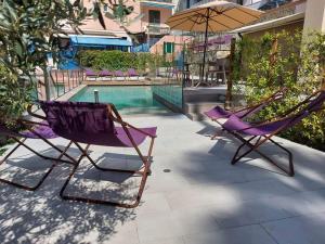 dos sillas y una sombrilla junto a una piscina en Hotel Zurigo, en Varazze
