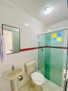 La salle de bains est pourvue de toilettes, d'un lavabo et d'une douche. dans l'établissement Pousada Riviera, à Caraguatatuba