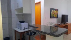 eine Küche mit einer Theke mit Stühlen und einer Mikrowelle in der Unterkunft Apto Flat Thermas Paradise, Rio Quente, Caldas Novas-Go in Rio Quente