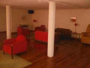 a living room with red chairs and a white pole at Hotel Alameda in Albergaria-a-Velha