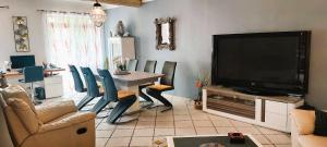 - un salon avec une télévision, une table et des chaises dans l'établissement Mas de l'Oratoire, à Saint-Rémy-de-Provence