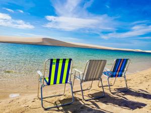 dos sillas sentadas en una playa cerca del agua en Dunas Residence - Casa 10, en Santo Amaro