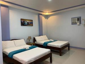 a room with two beds in a room at Merangie Travellers Inn in Dauis