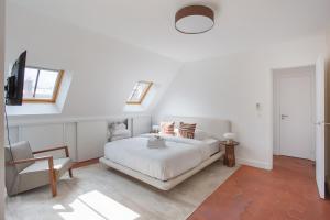 1 dormitorio blanco con 1 cama y 1 silla en Apartement Montaigne George V by Studio prestige, en París