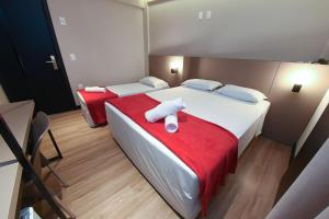 a bedroom with two beds with red sheets and white towels at Arco do Sol Park Hotel in Camboriú +106 photos