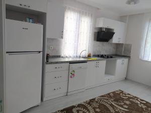 uma cozinha com armários brancos e um frigorífico branco em Yomra Villa Konaklama Günlük Kiralık em Yomra