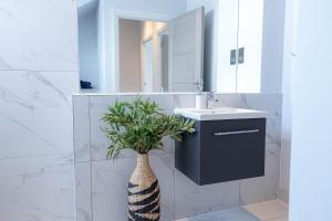 a bathroom with a sink and a vase with a plant in it at Stylish Apartments with Balcony for upper apartments & Free Parking in a prime location - Five Miles from Heathrow Airport in Uxbridge