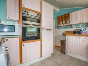 a kitchen with white cabinets and a microwave at 4 Greenbank Terrace in St Austell