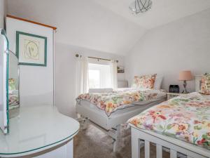 a bedroom with two beds and a table and a window at 4 Greenbank Terrace in St Austell