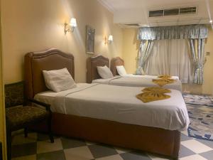 um quarto de hotel com duas camas e uma cadeira em Holidays Express Hotel no Cairo