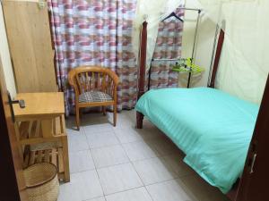 a room with a bed and a chair and a table at 3-Bedroom Mbarara Apartment with Optional Farm Tour in Mbarara