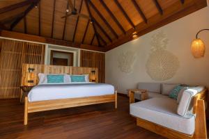 a bedroom with a bed and a couch at Barceló Whale Lagoon Maldives in Machchafushi