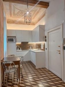 cocina con armarios blancos, mesa y sillas en Appartamento al Teatro Romano, en Verona