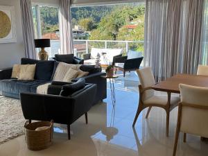 sala de estar con sofá azul y sillas en Cobertura Duplex - La Belle Vue - Canajurê, en Florianópolis