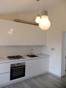 una cucina con mobili bianchi e un forno a piano cottura di Casa Baroncelli a Siena