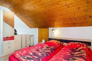 a bedroom with a red bed and a wooden ceiling at Dachwohnung Schneider Bingen in Mengen