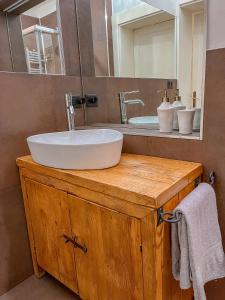 La salle de bains est pourvue d'un lavabo sur une coiffeuse en bois et d'un miroir. dans l'établissement Appartamento al Teatro Romano, à Vérone