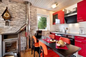 uma cozinha com armários vermelhos, uma mesa e cadeiras em Klug em Obertal