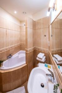 La salle de bains est pourvue d'une baignoire et d'un lavabo blanc. dans l'établissement Hotel Royal, à Gliwice