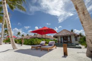 een paar stoelen en een parasol op het strand bij Barceló Whale Lagoon Maldives in Machchafushi