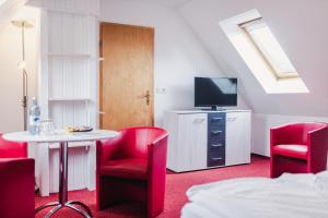 a room with red chairs and a table and a tv at Pension Schwalbenhof in Klausdorf Mecklenburg Vorpommern