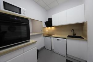 a kitchen with white cabinets and a black microwave at Loft 250m2 avec écran led géant de 10m2 in Marseille