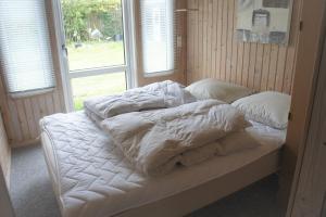 1 cama con sábanas y almohadas blancas en una habitación con ventana en (id 081) Åbakken 19, en Esbjerg