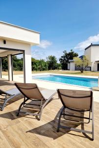 un patio con 2 sillas y una piscina en Le Gîte City Haut de gamme, Jardin, Piscine, en Gabriac