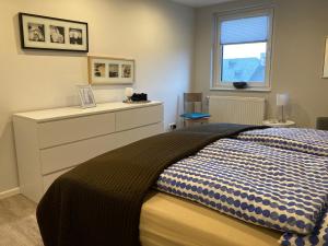 ein Schlafzimmer mit einem Bett mit einer Kommode und einem Fenster in der Unterkunft Kleine Auszeit, Schöne neue Ferienwohnung in Bitburg