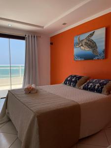 a bedroom with a bed with an orange wall at Praia das Tartarugas in Barra de Tabatinga