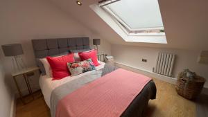 a bedroom with a bed with red pillows and a skylight at The Church View, Great for Contractors and groups, Easy access M1 in Markyatestreet
