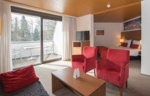 a hotel room with red chairs and a bed at Fletcher Hotel-Restaurant Wolfheze in Wolfheze