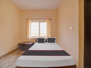 Cama grande en habitación con ventana en OYO Hotel Rajaganga Lodge en Hassan